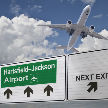 Road sign indicating the direction of Hartsfield-Jackson airport and a plane that just got up.